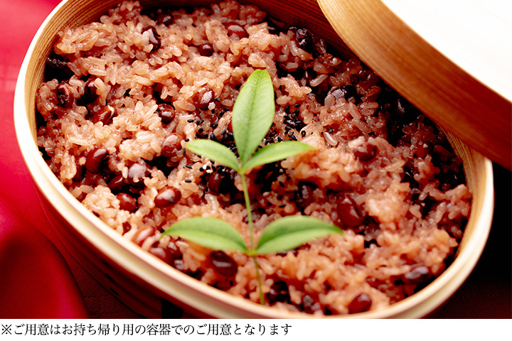 木製の飯器に盛り付けた小豆入りの赤飯に南天の葉を添えた祝い料理の写真