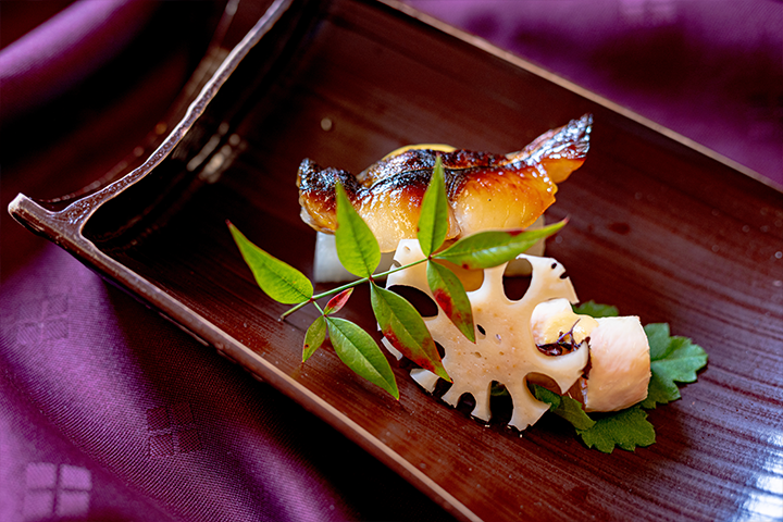 サワラの西京焼きとれんこん、木の葉のあしらいを添えた焼き物の盛り付け写真