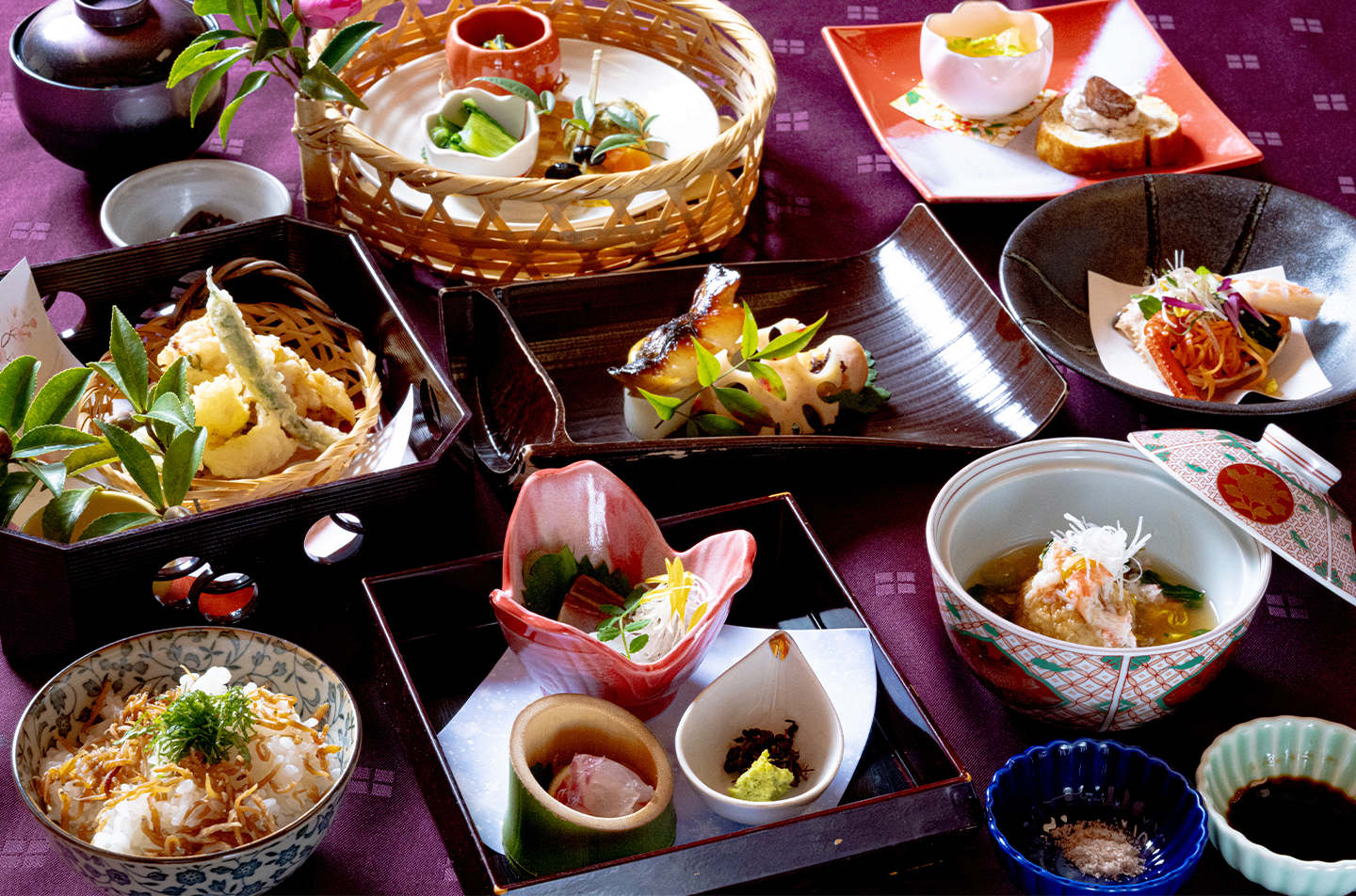 冬の会席料理の全体盛り付け。前菜、造り、煮物椀、焼き物、蒸し物、天ぷら、炊き込みご飯、甘味までを卓上に並べた和食のコース