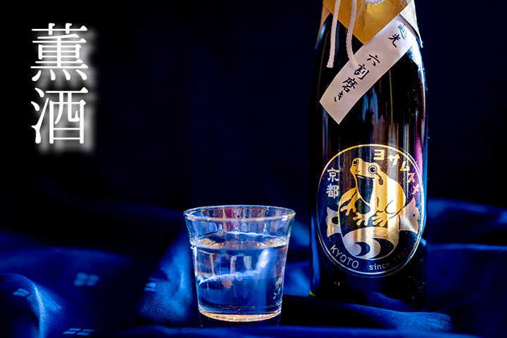 与謝娘酒造の日本酒ボトルとグラス。京都与謝野町産コシヒカリ使用、六割磨き表示。青い背景に金色のカエルのラベルが映える。