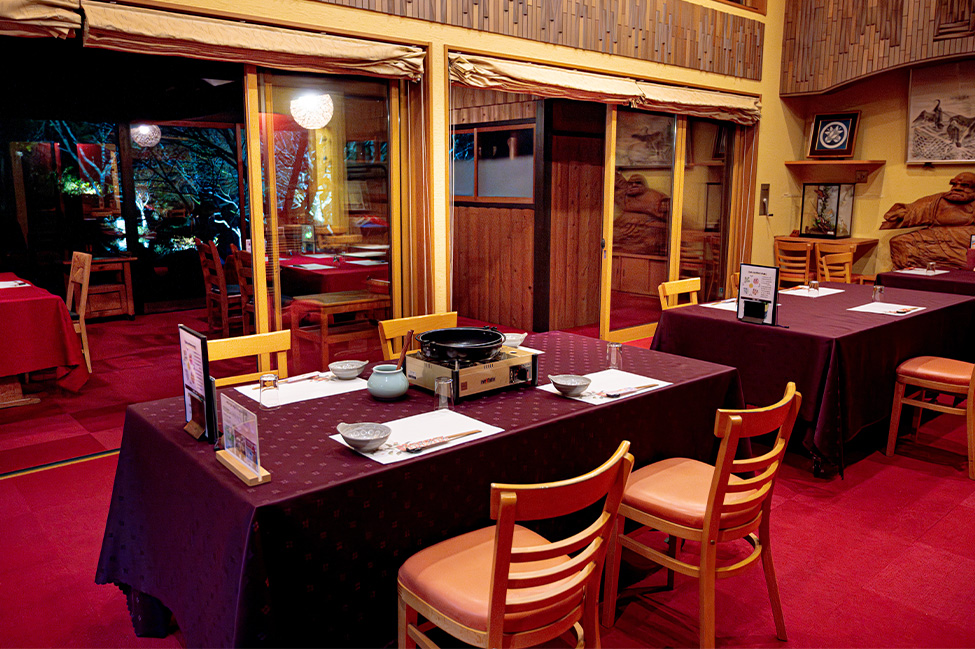 料亭ゆう月の個室会場。赤い絨毯と木の温もりある空間に、鍋料理用の卓上コンロを設えた落ち着いた和の食事席