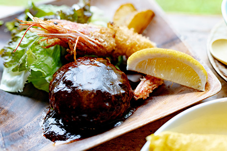 デミグラスソースをかけたオムライスをスプーンですくう瞬間。中のケチャップライスが見える温かい洋食ランチセット